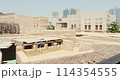 House in traditional Arabic architecture with wind tower. Traditional Arabic style building with windcatcher tower and palm leaves thatched roof. Old Dubai, UAE. View of rooftops of old Arab city 114354555