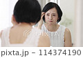 鏡を見ながら生え際を心配するミドル女性 鏡を見ながら生え際を心配するミドル女性 114374190