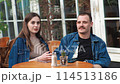 A young couple. Denim clothes. On a date in a vintage restaurant, outside. They are talking. Fooling around 114513186