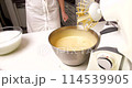 Confectioner kneads dough in a mixer for baking a cupcake 114539905