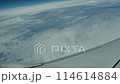 航空機の窓から眺めた旋回する飛行機の翼と美しい雲海のシーン 114614884