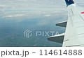 旅客機の窓から眺めた地上の風景と白い雲が流れるシーン 114614888