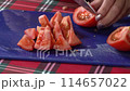 Woman's hands using kitchen knife cutting fresh tomato on plastic cutting board. Healthy eating. Sliced tomato. 114657022