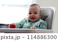 Cute Baby Boy Sitting in High Chair Eating a Strawberry. Home, Mealtime 114886300