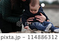 Mother holding cute baby boy while he sits on Rocky River Shore. Sunset, Spring Season. Chilliwack 114886312