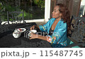 Asian woman is sitting on black iron table and drinking tea on a terrace, enjoy morning fresh air with view 115487745