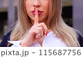 Close-up Businesswoman looking at camera with defiant gesture outdoors 115687756