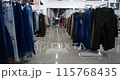 Dollying shot of camera moving through aisle in fashion store and passing by racks of carefully arranged clothing 115768435