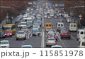 Blurred video of a bustling street with numerous cars, buses, trucks and pedestrians. 115851978