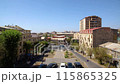 A panoramic view of the cityscape with blue sky, trees, cars, people, and buildings on a sunny summer day. Time Lapse video 115865325