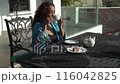 Asian woman is sitting on black iron table and drinking tea on a terrace, enjoy morning fresh air with view 116042825