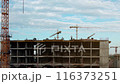 Aerial view, construction workers on the roof of a multi-story modern building under construction pouring concrete. Construction of a residential apartment building or office center.  116373251