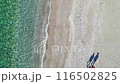 Two women walking near the turquoise sea at beach 116502825
