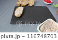 Girl putting down a sandwich bread with meat pate on a black tray. Preparing breakfast 116748703