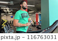 man drinking water while walking on race track or running machine in gym trying to slenderize 116763031