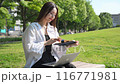 在公園長椅上拿著筆記本的年輕女子 116771981