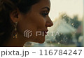 クローズアップ：黄金色の朝日に包まれた女性の横顔。ソフトフォーカスが穏やかな表情を捉える 116784247