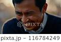 アジア人男性が前かがみになり、目を見開いて興奮している。ネイビーのセーター、希望に満ちた表情 116784249