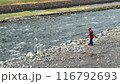 man trimming grass between rocks by mountain river 116792693