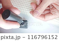 Gel polish manicure step-by-step video tutorial. Step 7 Nails base coat. A woman applies a gel polish base coat with a rubbing motion on her thumbnail for better adhesion 116796152