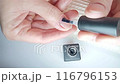 Gel polish manicure step-by-step video guide. Step 7 Nails base coat. A woman covers her thumb with a base gel coating and caps the nail's free edge. At-home manicure concept 116796153