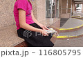 A girl on the street near a bank is counting large dollar bills. 116805795