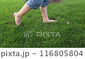 A small child walks barefoot on green grass. 116805804