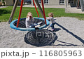 Little children ride on a swing. Two girls ride each other and play on the playground. 116805963