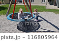 Little children ride on a swing. Two girls ride each other and play on the playground. 116805964