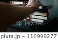 A man's hand loads a VHS cassette into a VCR. 116999277