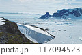 Majestic winter Antarctic aerial landscape. Frozen polar ocean, green rock hill, icebergs, snow covered mountains, seagulls flying in blue sky. Antarctica travel exploration. Explore South Pole nature 117094523