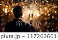 Man in a suit holding a glass of champagne against a sparkling, festive background 117262601