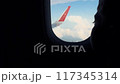 dark silhouette of boy looking out the Window in plane at aerial view. Clouds and aircraft wing. 117345314
