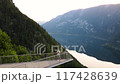 Young man is staying on the viewing platform with drone controller view of Alps mountains and lake 117428639