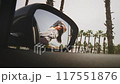 Reflection of cheerful young woman in sunglasses leaning out of car window in side mirror of vehicle 117551876