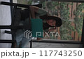 A woman in headphones sits on a chair hold use smartphone watching social media and shopping online sale. 117743250