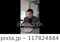 Young Asian businessman typing messages or reading news on his smartphone 117824884
