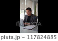 Young Asian businessman typing work information on his laptop at the work desk.  117824885