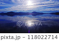 薄い雲の広がる青空に光る眩しい太陽の光を湖面に反射する雄大な湖。水面には穏やかなさざ波。 118022714