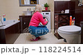 Blonde woman inspecting freshly washed blouse in a small European bathroom after laundry 118224514