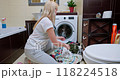 Woman sorting laundry on the bathroom floor, separating whites from colors 118224518