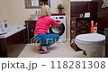 Woman with a slender figure examines freshly laundered blouse in a bright, cozy European bathroom after finishing laundry 118281308