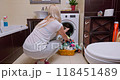 Woman in her 30s unloading laundry from washing machine, preparing clothes for drying in a bright bathroom 118451489