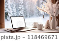 Cozy winter workspace with a laptop and warm coffee, featuring a snowy forest view, ideal for remote work and holiday inspiration. looping 4K video animation and laptop mockup. 118469671