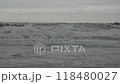 Waves crashing against breakwater rocks during gloomy weather. 118480027