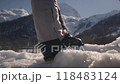 Male skier puts foot on snowdrift securing ski boots by tightening clips against snowy mountain 118483124