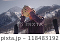 Sporty man skier in ski goggles adjusts hair putting on helmet standing against snowy mountains 118483192