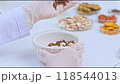 Experimental video sample with a close-up of a scientist dropping cloves into a white mortar containing poria cocos wolf placed on a table, surrounded by herbal ingredients contained in petri dishes. 118544013