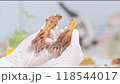 The background suggests a lively laboratory with a variety of herbal specimens. Scientists are held up by a gloved hand and observe two dried ginseng pieces. 118544017