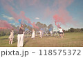 Group of students people are walking in a field, having fun with colored smoke. 118575372